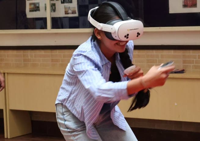 A student mid-session in a VR headset, controllers in hand, during a Kashti immersive-technology workshop in a school hall